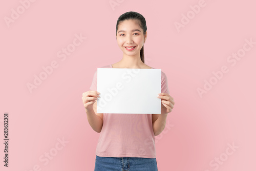 Young Asian woman holding blank paper with smiling face and looking on the blue background. for advertising signs.