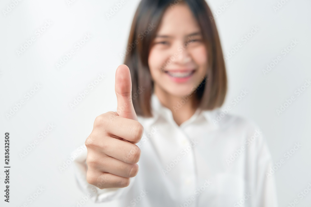 Smiling Asian woman and showing thumbs up or like on gray background. Smiling Asian woman and showing thumbs up or like on gray background.