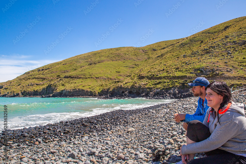 A couple enjoy the peacefulness of the scenic view at one of the bays on Banks Peninsula while out on a day trip