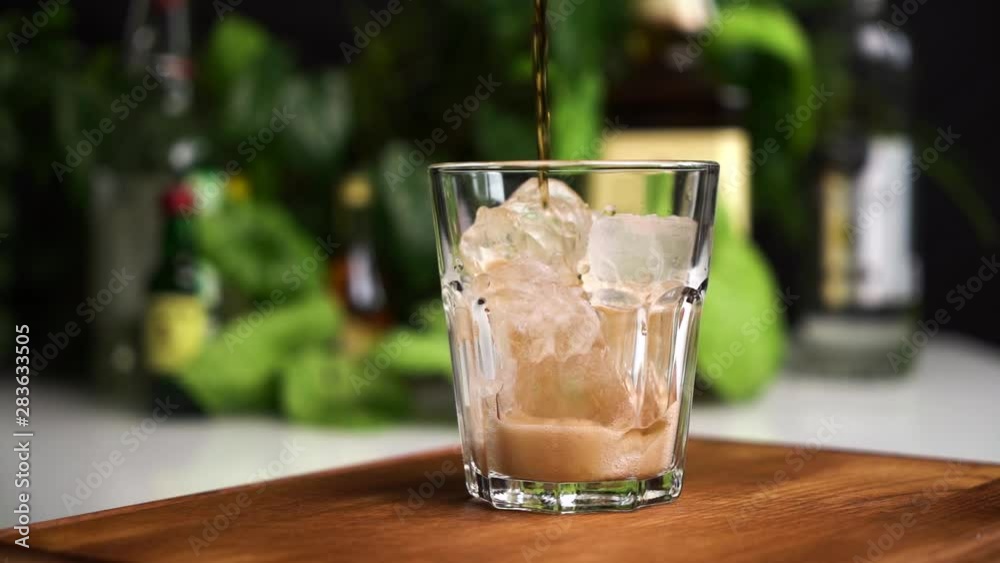 Slow motion of pouring Cola with ice cubes close-up. Cola with Ice and bubbles in glass. Coke Soda closeup. Food background. Slow motion of pouring Cola with ice cubes close-up. Cola with Ice and bubbles in glass. Coke Soda closeup. Food background.
