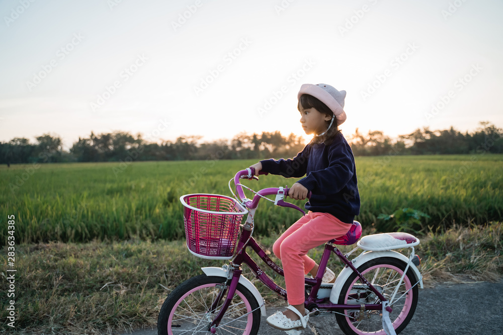 happy kid girl riding her bicycle outdoor during sunset happy kid girl riding her bicycle outdoor during sunset