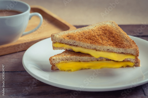 Grilled cheese sandwich on plate and coffee cup.