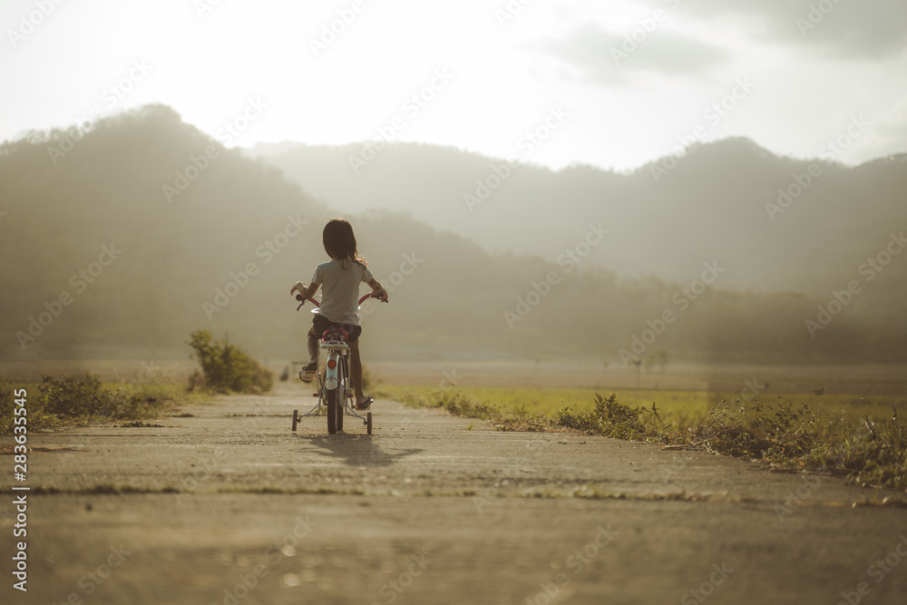 toddler enjoy riding her bicycle outdoor in beautiful day