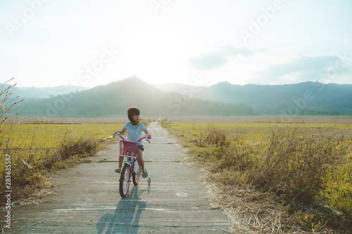 toddler enjoy riding her bicycle outdoor in beautiful day