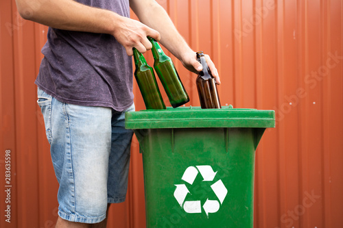 Man putting glass bottles in recycle bin  photo