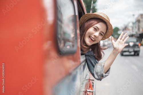 Smiling woman traveler in thapae gate landmark chiangmai thailand sitting on the red bus with backpack on holiday, relaxation concept, travel concept