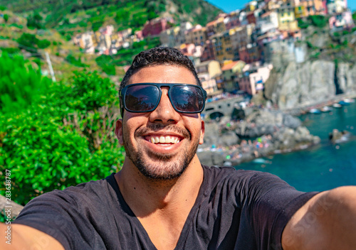 Young man selfie on sunny day with blue sky in Cinque Terre, Italy. European summer.