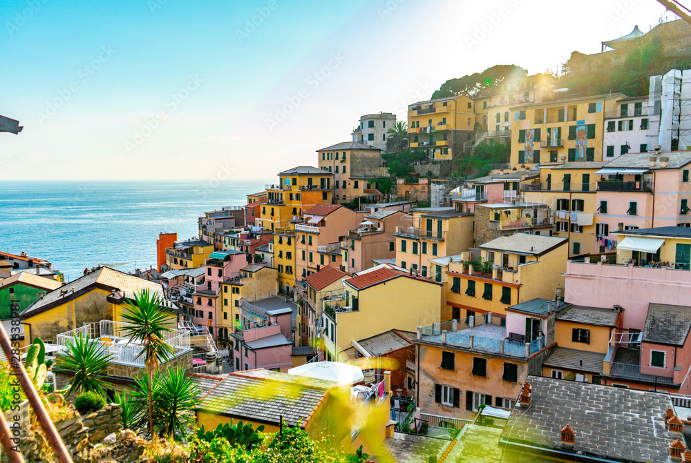 Amazing view of the village of Riomaggiore in Cinque Terre, Liguria in Italy. Sunset time with the colorful houses. European summer and Mediterranean sea.
