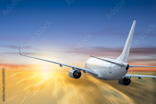 White airplane flying above cloud at sunset