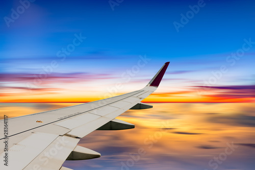 Airplane wing in the sky on sunset sky background