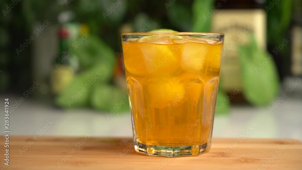 Slow motion of slices of lime fall into orange soda in glass with ice Slow motion of slices of lime fall into orange soda in glass with ice