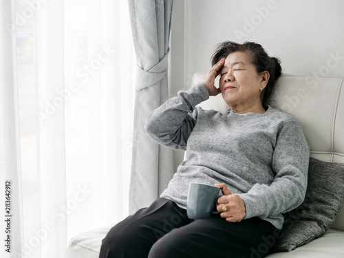 Asian senior woman having headache at home, health care concept. © nuiiko