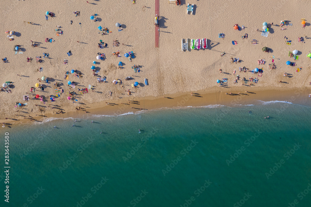 People on vacation on beautiful beach, Praia da Luz, Algarve, Portugal, summer aerial drone wide view