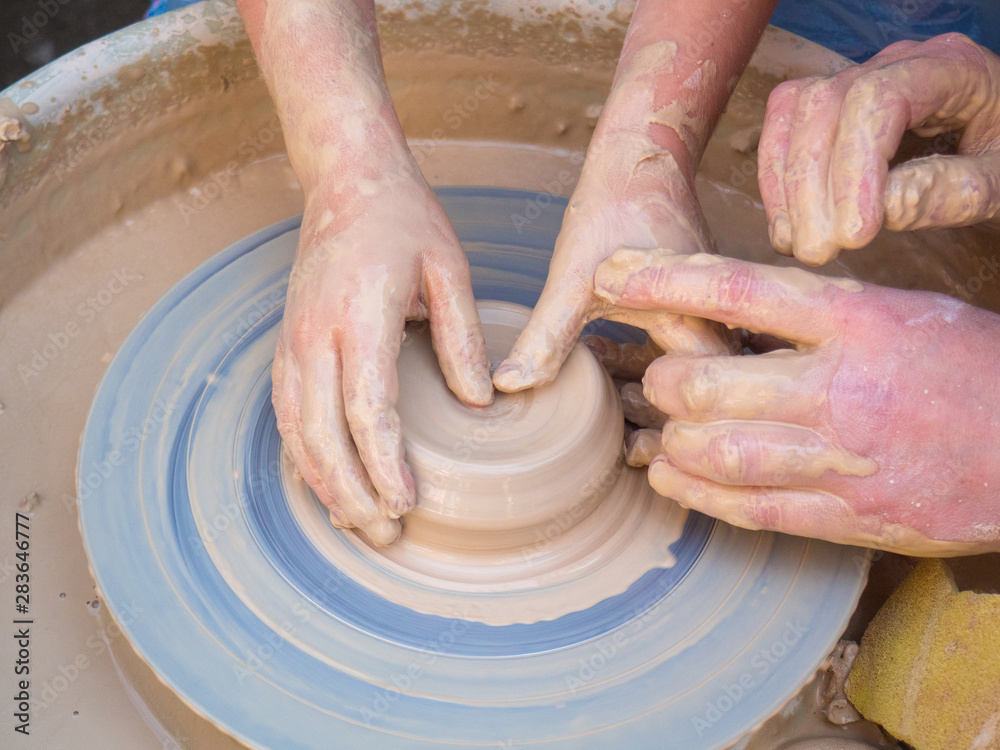 Master class on modeling of clay on a potter's wheel In the pottery workshop for children sunny day four hands. Concepts: handmade, studying, master class, workshop, pottery, skill, creativity