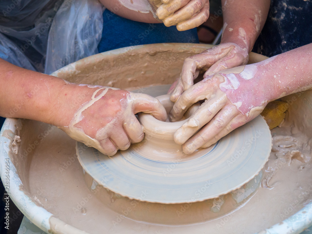 Master class on modeling of clay on a potter's wheel In the pottery workshop for children sunny day three hands. Concepts: handmade, studying, master class, workshop, pottery, skill, creativity