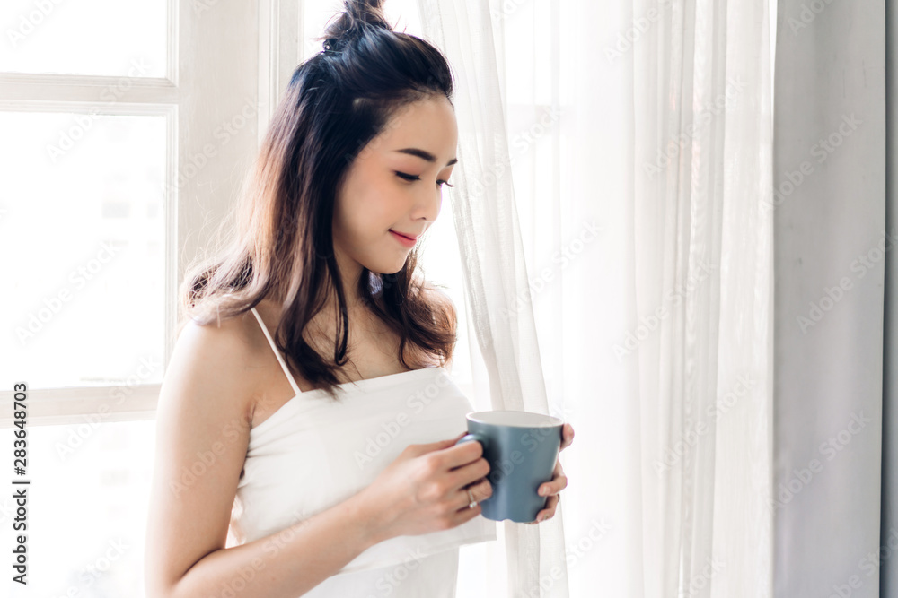 Woman drinking coffee in bedroom in the morning Woman drinking coffee in bedroom in the morning