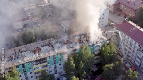 Burning roof of a residential high-rise building, clouds of smoke from the fire. firefighters extinguish the fire. top view