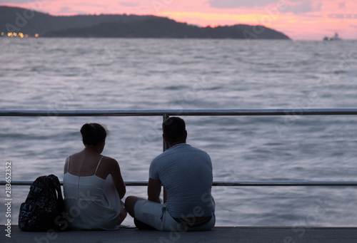 couple relax in front of the sea with sunset view. © Kanphitcha