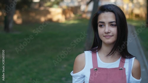 Cute stylish young woman walking outdoors in the green park in a summer day, Slow motion