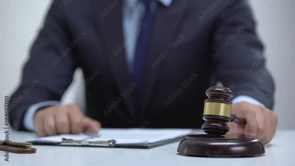 Male judge signing document banging gavel on block, court determines sentence Male judge signing document banging gavel on block, court determines sentence
