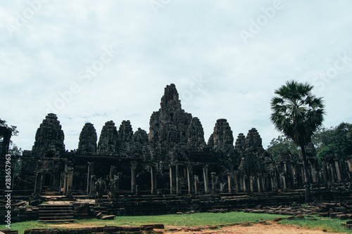 UNESCO World Heritage 1992 - Large face shaped statues in temple ruins in Ankgor Thom, Cambodia surrounded by a blue sky