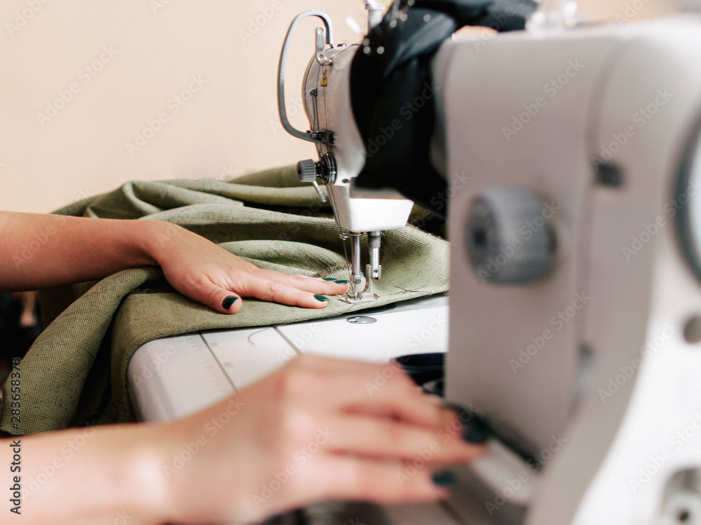 Upholstery manufacturing. Cropped shot of seamstress working with sewing machine in tailor studio.