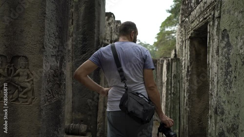 Man sightseeing ancient Angkor Wat temple ruins in Cambodia photo