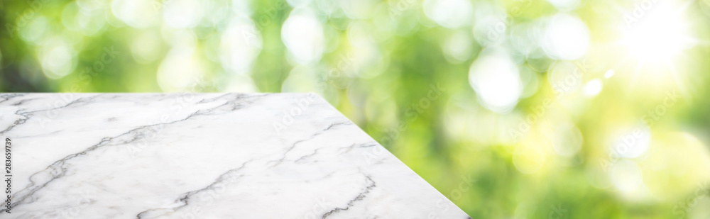 Obraz premium marble table top product display background with blur nature garden.left perspective wooden kitchen counter with green leaf and sunlight.Banner mockup presentation for your product on online media