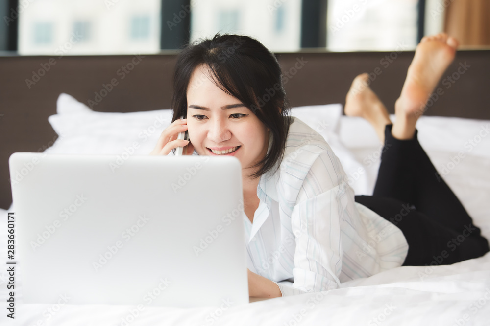 Happy asian business woman talking with cell phone laying down on the bed. Happy asian business woman talking with cell phone laying down on the bed.