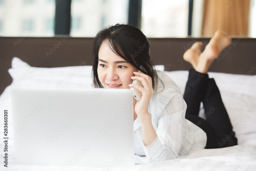 Happy asian business woman talking with cell phone laying down on the bed. Happy asian business woman talking with cell phone laying down on the bed.