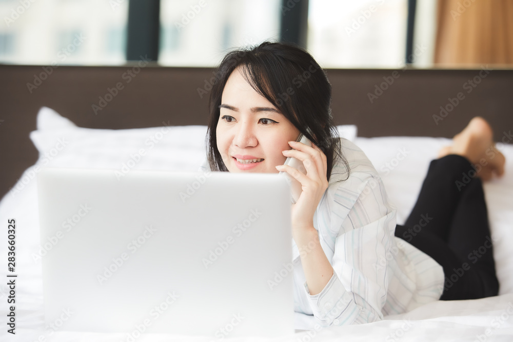 Happy asian business woman talking with cell phone laying down on the bed. Happy asian business woman talking with cell phone laying down on the bed.