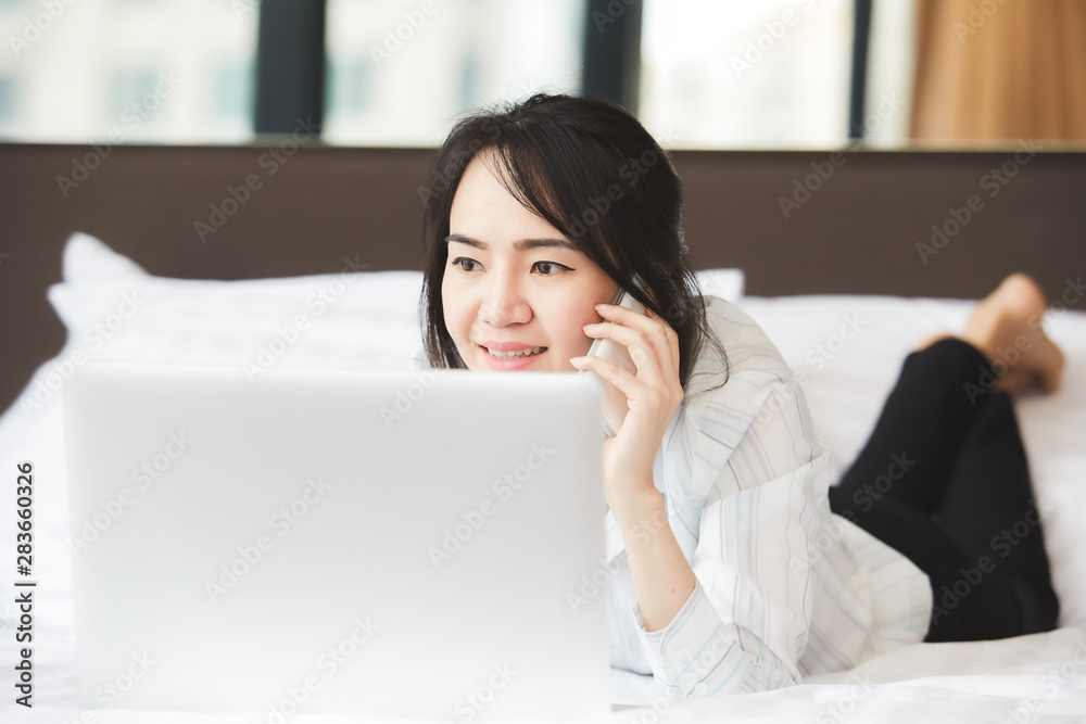 Happy asian business woman talking with cell phone laying down on the bed. Happy asian business woman talking with cell phone laying down on the bed.