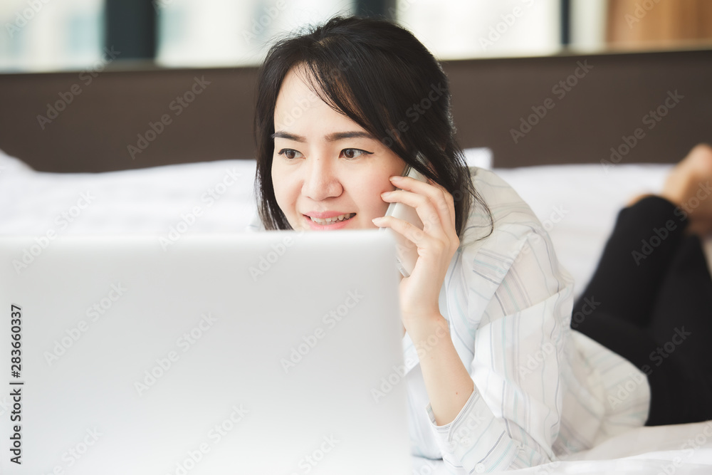 Happy asian business woman talking with cell phone laying down on the bed. Happy asian business woman talking with cell phone laying down on the bed.
