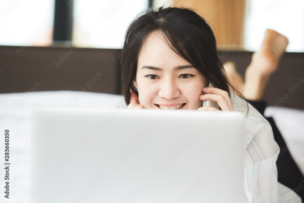Happy asian business woman talking with cell phone laying down on the bed. Happy asian business woman talking with cell phone laying down on the bed.