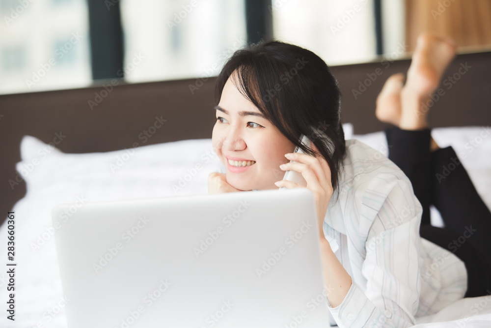Happy asian business woman talking with cell phone laying down on the bed. Happy asian business woman talking with cell phone laying down on the bed.