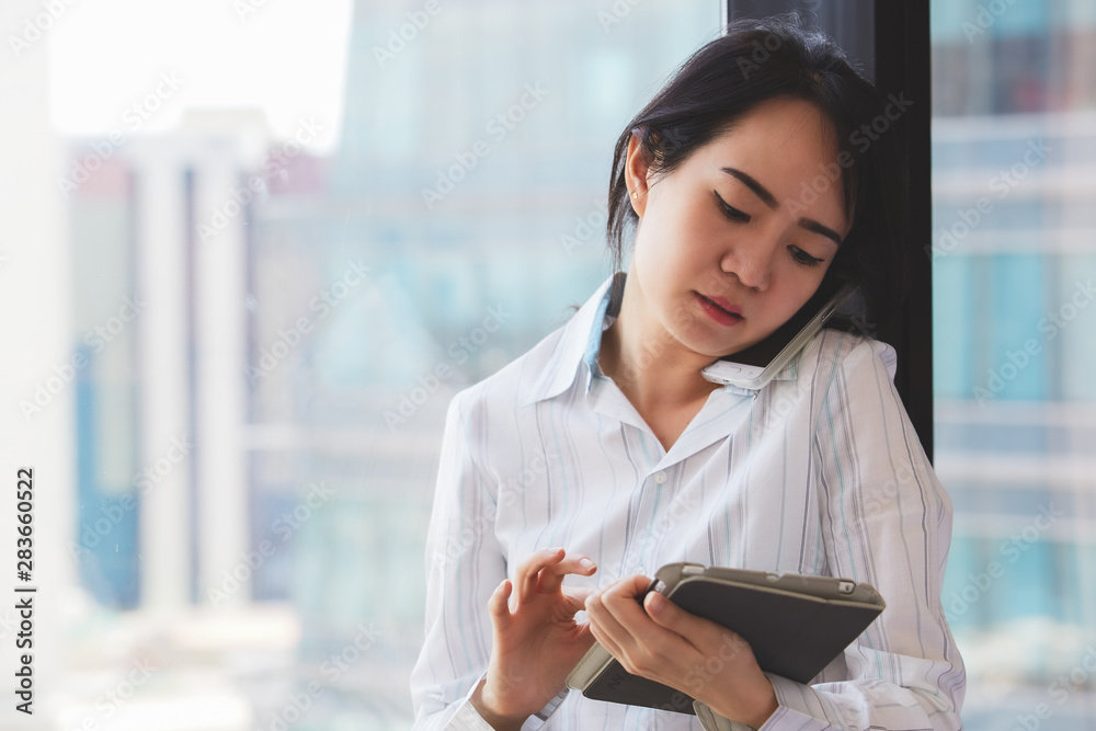 Happy asian business woman talking the phone and holding tablet computer at the working place. Happy asian business woman talking the phone and holding tablet computer at the working place.