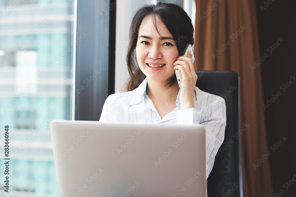 Asian business woman in smile face are using mobile phones and laptops in the office. Asian business woman in smile face are using mobile phones and laptops in the office.