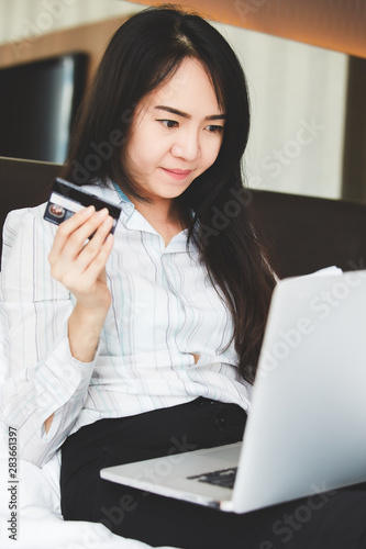 Portrait asian beautiful women are using credit cards and mobile phone to shopping online in the bedroom.