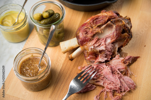 Gegrilltes Schweinefleisch Haxen Fleisch auf Holzbrett mit Cornichons, süßen und mittelscharfen Senf auf Marmor Hintergrund photo