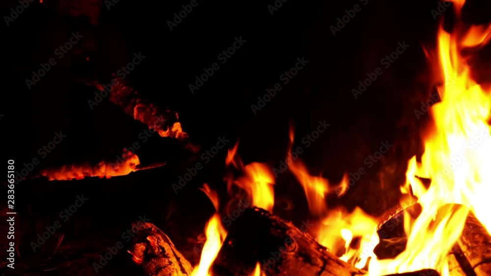 Close up video of a campfire. Wooden sticks whit bread dough wrapped around it enter the scene from the side, as the bread bakes slowly. The video is dark, with the fire as the only light source Close up video of a campfire. Wooden sticks whit bread dough wrapped around it enter the scene from the side, as the bread bakes slowly. The video is dark, with the fire as the only light source