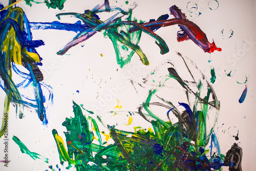 A little boy painting with watercolors on white paper sheet. Little boy with a brush and colorful paints.  Back to school concept. Copyspace.