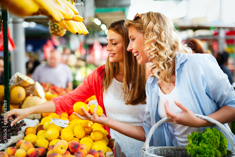 Φωτογραφία Young happy women shopping vegetables and fruits on the market