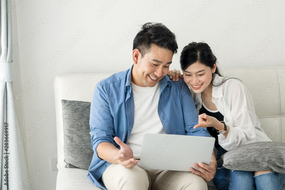 Happy Asian couple shopping online with holding credit card and laptop and sitting at home together, lifestyle concept. Happy Asian couple shopping online with holding credit card and laptop and sitting at home together, lifestyle concept.