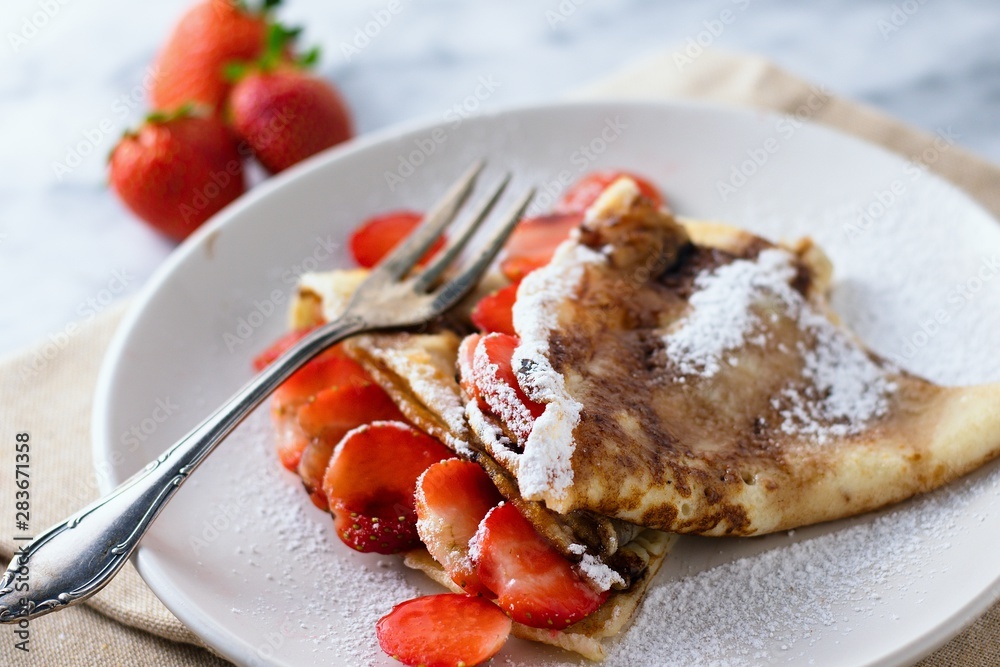 Triangle folded crepes with strawberries and powdered sugar Triangle folded crepes with strawberries and powdered sugar