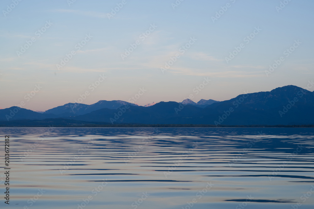 Blick auf die Alpen vom Boot auf dem Chiemsee während der blauen Stunde