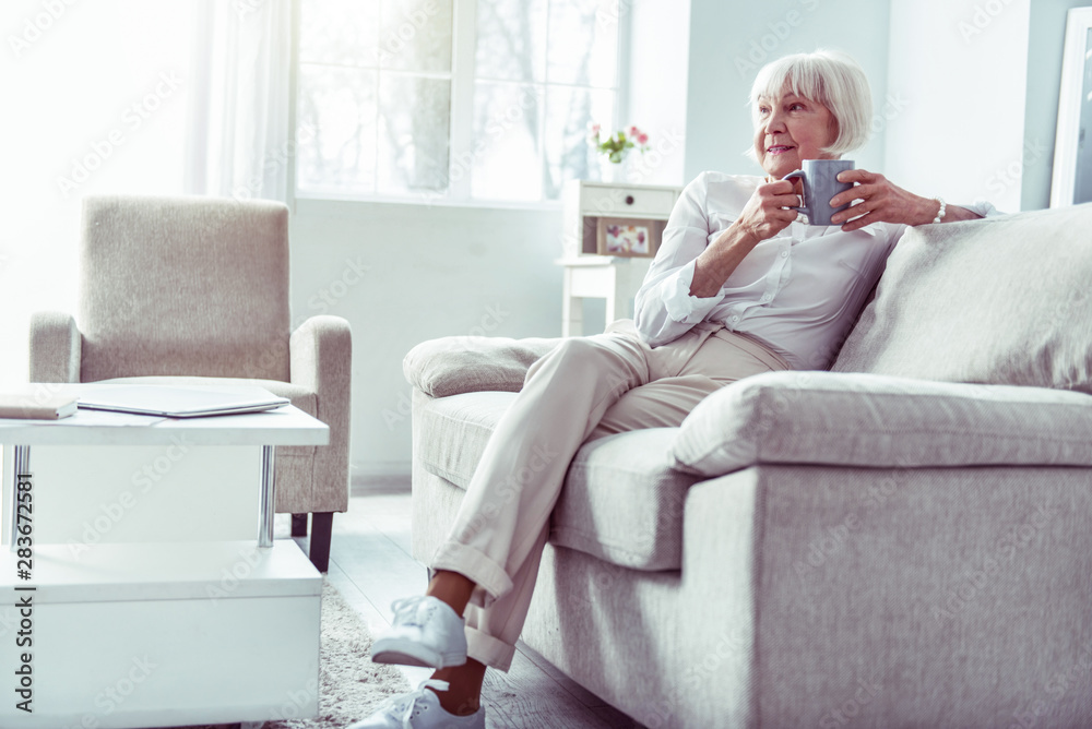 Retired woman wearing beige trousers and white blouse waiting for husband Retired woman wearing beige trousers and white blouse waiting for husband
