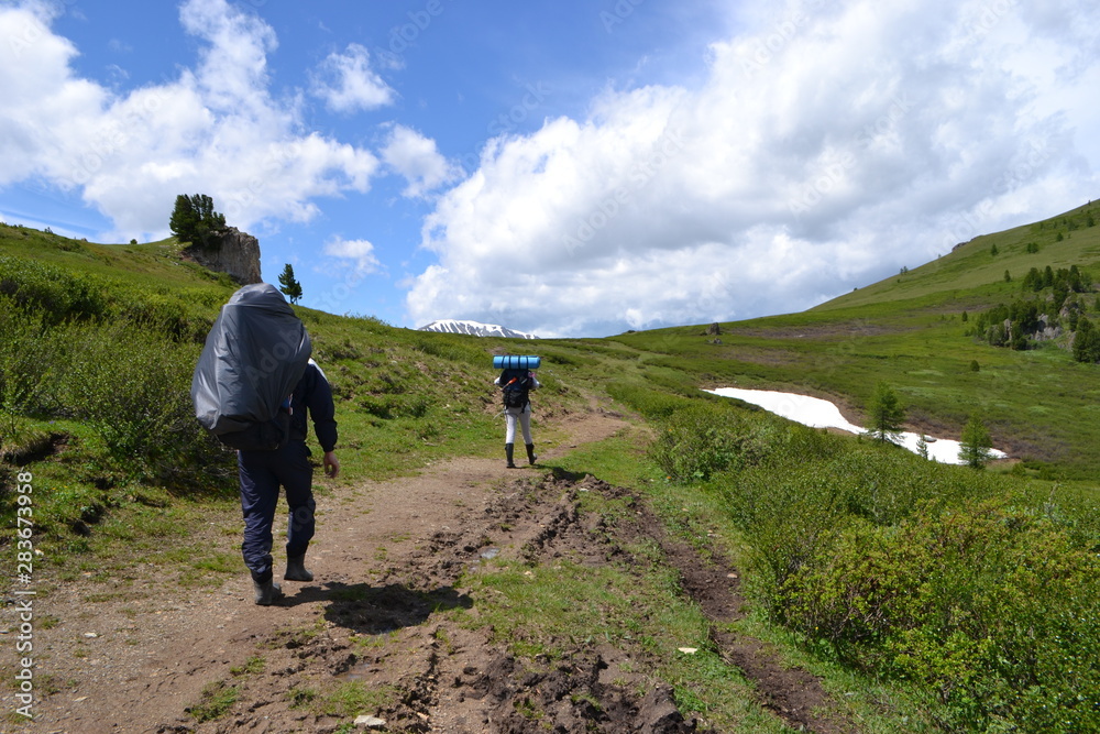 tourists walk with a big backpack on a mountainous landscape tourists walk with a big backpack on a mountainous landscape