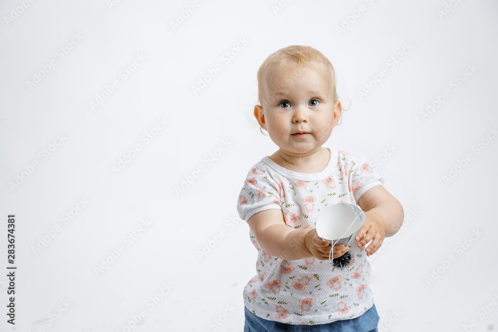 A little cute happy girl rejoices and laughs on her first birthday on a white background. Slapstick with confetti, a balloon filled with helium, a silver cap. A little cute happy girl rejoices and laughs on her first birthday on a white background. Slapstick with confetti, a balloon filled with helium, a silver cap.