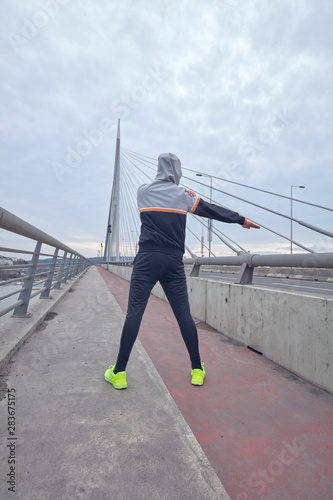 Sportsman working out / jogging on a big city urban bridge.