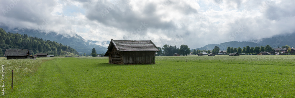 Panorama landscape. Old wooden hut on alpine meadows with mountains in background